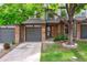 Inviting townhome featuring brick accents, a gray garage door, and a well-manicured lawn with a mature shade tree at 1953 E 102Nd Cir, Thornton, CO 80229