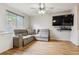 Cozy living room with hardwood floors, a comfortable gray sofa, ceiling fan, and a mounted TV at 1953 E 102Nd Cir, Thornton, CO 80229