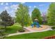 Community playground with slides, climbing structure, and a wood chip base surrounded by green grass at 1953 E 102Nd Cir, Thornton, CO 80229