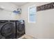 Functional laundry room with modern appliances, storage shelf, and bright window at 1846 Osprey Dr, Brighton, CO 80601
