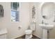 Powder room with pedestal sink, round mirror and soft natural light at 1846 Osprey Dr, Brighton, CO 80601