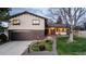Inviting home exterior with brick accents, well-lit porch, and manicured front lawn with a large bare tree in the yard at 7290 Lamar Ct, Arvada, CO 80003