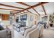 Open-concept living room and dining area featuring exposed beams, lots of natural light, and neutral decor at 7290 Lamar Ct, Arvada, CO 80003