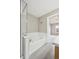 Bright bathroom with white tiled walls, a large soaking tub, and access to bedroom at 4108 W 118Th Pl, Westminster, CO 80031