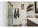 Bathroom featuring a glass enclosed shower, toilet, and vanity with open shelf storage at 5415 S Delaware St, Littleton, CO 80120
