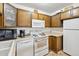 Efficient kitchen featuring wood cabinets and white appliances at 655 S Alton Way # 4B, Denver, CO 80247