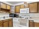 Galley kitchen with wood cabinets and white appliances at 655 S Alton Way # 4B, Denver, CO 80247