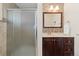Stylish bathroom featuring a glass shower, wood vanity, and mosaic tile at 930 Reed Ct, Lakewood, CO 80214