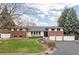 Well-manicured home exterior featuring a lush front lawn, mature trees, and a classic brick and siding facade at 930 Reed Ct, Lakewood, CO 80214