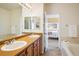Spacious bathroom featuring dual sinks, vanity storage, and a tub with tiled surround at 1122 Olympia Ave # 12H, Longmont, CO 80504