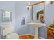 Charming powder room with a pedestal sink, stylish mirror, and blue walls at 6700 W Dorado Dr # 51, Littleton, CO 80123