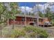 Cabin home with wood siding and a deck, surrounded by lush greenery and aspen trees at 26367 Pressler St, Conifer, CO 80433