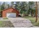 A spacious garage with wood siding and a concrete driveway surrounded by mature trees at 26367 Pressler St, Conifer, CO 80433