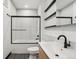 Modern bathroom features a sleek vanity, a tub with glass doors, and stylish black hardware at 1601 Park Ave # 106, Denver, CO 80218