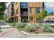 Modern condo building featuring wood paneling, black accents, and landscaped front yard at 1601 Park Ave # 106, Denver, CO 80218