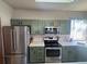 Green-cabinet kitchen with stainless steel appliances, tiled countertops, and ample cabinet space at 1517 Stanley Dr, Erie, CO 80516