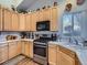 L-shaped kitchen with wood cabinets and stainless steel appliances at 2576 S Ensenada Way, Aurora, CO 80013