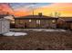 The backyard is spacious with a shed, partial snow, and the sky is painted with vivid sunset colors at 2042 Jamaica St, Aurora, CO 80010