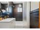 Dark tiled bathroom with gold fixtures, white vanity, and bathtub shower combination at 2042 Jamaica St, Aurora, CO 80010