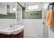 The bathroom features a wooden vanity, white tiled walls, and a large mirror, blending functionality with a clean design at 2042 Jamaica St, Aurora, CO 80010