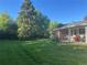 Large, grassy backyard featuring mature trees and a partially covered patio with outdoor seating at 3201 S Albion St, Denver, CO 80222