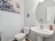 Bright powder room features a pedestal sink, toilet, and round mirror at 3662 S Perth Cir # 104, Aurora, CO 80013