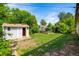 A spacious backyard featuring a storage shed, a small wooden fence, lush greenery, and a charming stone walkway at 6953 Ingalls St, Arvada, CO 80003