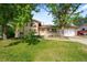 A well-kept lawn complements this charming two-story home with mature trees and a welcoming front entrance at 6953 Ingalls St, Arvada, CO 80003