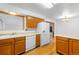 A well-equipped kitchen with wood cabinets and white appliances, adjacent to the dining area for seamless meal service at 6953 Ingalls St, Arvada, CO 80003