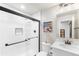 Modern all-white bathroom with glass shower, tile surround, and sleek black fixtures at 17786 W 86Th Ln, Arvada, CO 80007