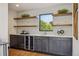 Modern bar area featuring dark cabinetry, quartz countertop, floating wood shelves, wine fridge, and a large window at 1100 S Gilpin St, Denver, CO 80210