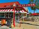 Exterior of Bonnie Brae Ice Cream parlor showing it's iconic sign, red and white striped awning, and outdoor seating at 1100 S Gilpin St, Denver, CO 80210