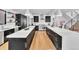 Spacious kitchen featuring black cabinetry, stainless steel appliances, a large island and hardwood floors at 1100 S Gilpin St, Denver, CO 80210