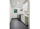 Well-lit laundry room with dark grey, front loading washer and dryer, white cabinets and black hexagon tile flooring at 1100 S Gilpin St, Denver, CO 80210
