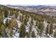 An aerial view of a home with mountain views, nestled in a wooded area on a snowy hillside at 1580 Santa Fe Mountain Rd, Evergreen, CO 80439