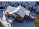 Aerial view of snow-covered house with brown siding and a deck surrounded by pine trees at 1580 Santa Fe Mountain Rd, Evergreen, CO 80439