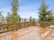 A wooden back deck is surrounded by tall trees and a wooden fence, with a mountain range in the background at 1580 Santa Fe Mountain Rd, Evergreen, CO 80439