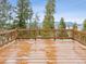 A wooden back deck is surrounded by tall trees and a wooden fence, with a mountain range in the background at 1580 Santa Fe Mountain Rd, Evergreen, CO 80439