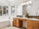 Bright bathroom featuring a large window, a soaking tub, double sinks, and wood cabinets at 1580 Santa Fe Mountain Rd, Evergreen, CO 80439