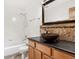 Bathroom with vessel sink, decorative backsplash, and shower-tub combo at 1580 Santa Fe Mountain Rd, Evergreen, CO 80439