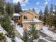 Two-story home with an attached two-car garage nestled among snow-covered grounds and mature trees at 1580 Santa Fe Mountain Rd, Evergreen, CO 80439