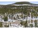 Aerial view of a single Gathering home nestled in a heavily wooded area, covered in winter snow and winding roads at 1580 Santa Fe Mountain Rd, Evergreen, CO 80439