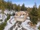 Lovely home exterior featuring an attached garage and a stone pathway, nestled in a snow-covered landscape with tall trees at 1580 Santa Fe Mountain Rd, Evergreen, CO 80439