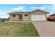 Tan home featuring a paved driveway, two-car garage, and well maintained lawn at 1882 S Zinnia Way, Lakewood, CO 80228