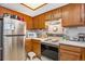 Functional kitchen with stainless steel refrigerator, white appliances, and wood cabinets at 9365 W 80Th Pl # C, Arvada, CO 80005