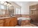 Bathroom featuring a soaking tub, glass enclosed shower, warm stone and wood finishes, and double sinks at 1907 S Columbine St, Denver, CO 80210