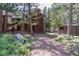 An outdoor shot showing the side of the home, a rock garden, and a gravel driveway through mature trees at 133 Mine Ln, Boulder, CO 80302