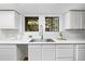 Clean, all-white kitchen with a stainless steel sink, modern faucet, and natural light from the windows at 133 Mine Ln, Boulder, CO 80302