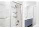 Bathroom with tiled shower, floating shelves, and vanity with blue cabinets at 7877 E Mississippi Ave # 901, Denver, CO 80247