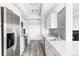 Galley kitchen with white cabinets, stainless appliances, light wood floors, and view to fireplace at 7877 E Mississippi Ave # 901, Denver, CO 80247